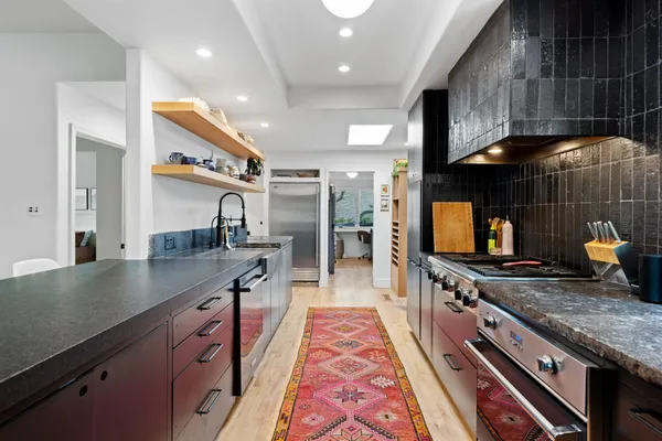 a kitchen with stainless steel appliances granite countertop a large stove a sink dishwasher and cabinets with wooden floor