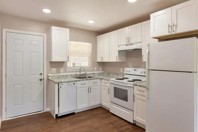 a kitchen with stainless steel appliances granite countertop a sink a stove a refrigerator and white cabinets