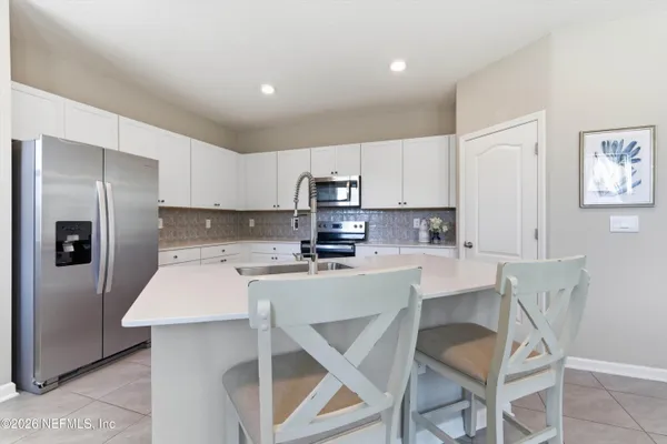 a kitchen with a refrigerator a stove a sink and white cabinets with wooden floor