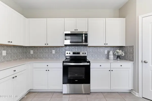 a kitchen with white cabinets and black appliances
