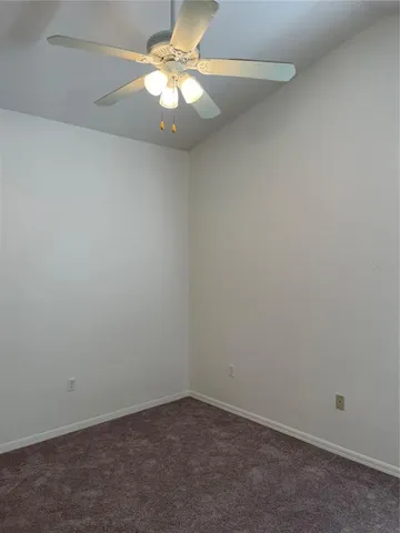 an empty room with a chandelier fan and windows