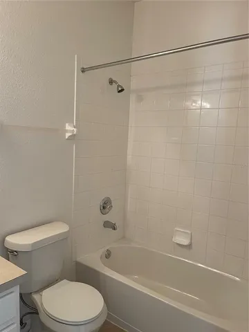 a white toilet and shower sitting next to a bathroom sink