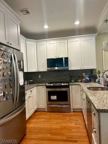 a kitchen with stainless steel appliances granite countertop a stove a sink and a refrigerator