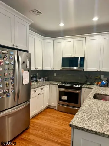 a kitchen with granite countertop a refrigerator stove and microwave