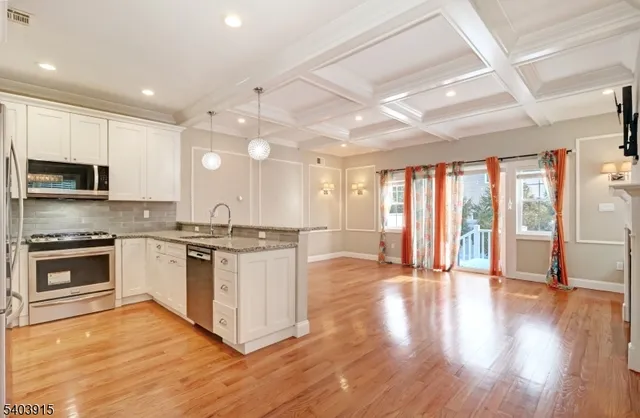 a large kitchen with stainless steel appliances granite countertop a stove and a wooden floors