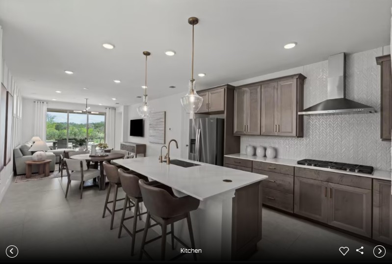 1000 Martingale Street Georgetown, TX 78633 - Photo 10 of 13 a kitchen with stainless steel appliances kitchen island granite countertop a stove a sink a dining table and chairs with wooden floor