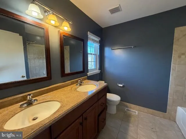 a bathroom with a granite countertop double vanity sink and a mirror