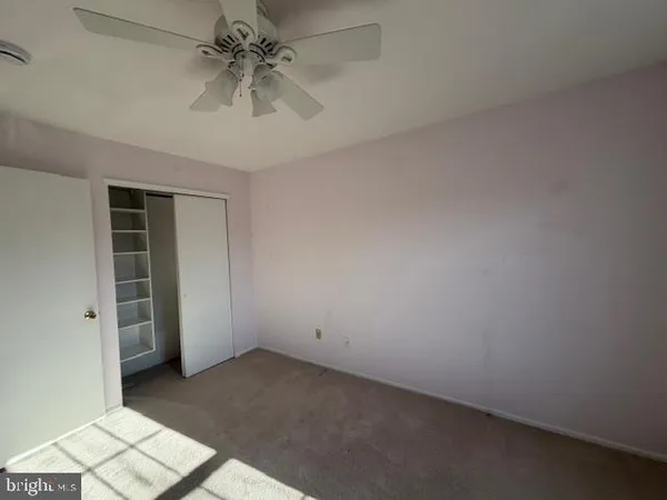 an empty room with chandelier fan and windows
