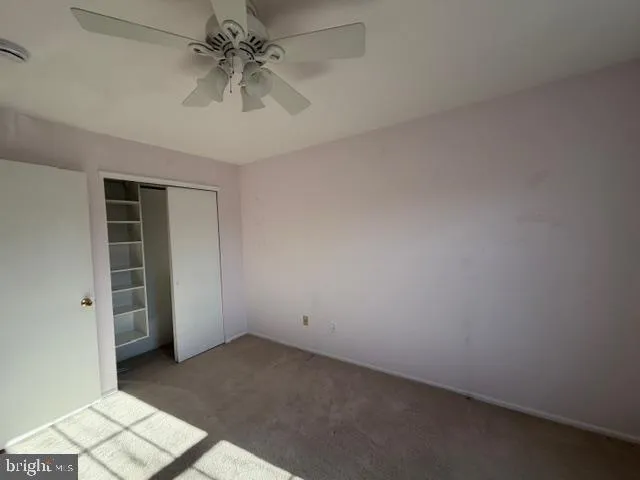 an empty room with chandelier fan and windows