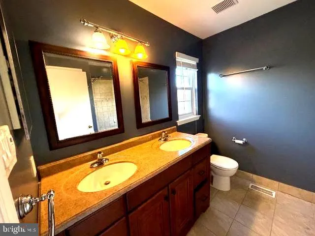 a bathroom with a granite countertop sink toilet and mirror