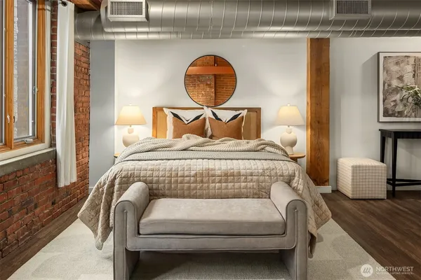 a bedroom with a bed a painting on the wall and a window