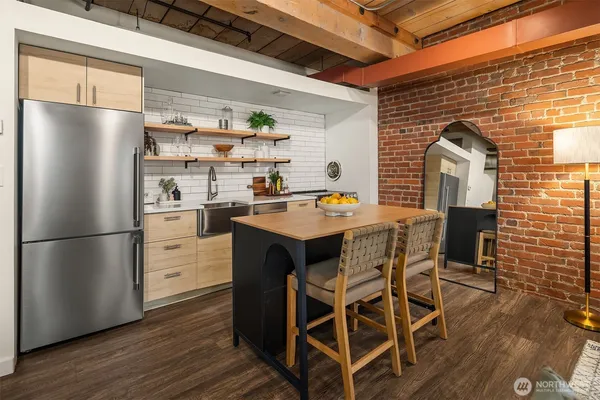 a kitchen with stainless steel appliances granite countertop a refrigerator a sink a stove and wooden floors