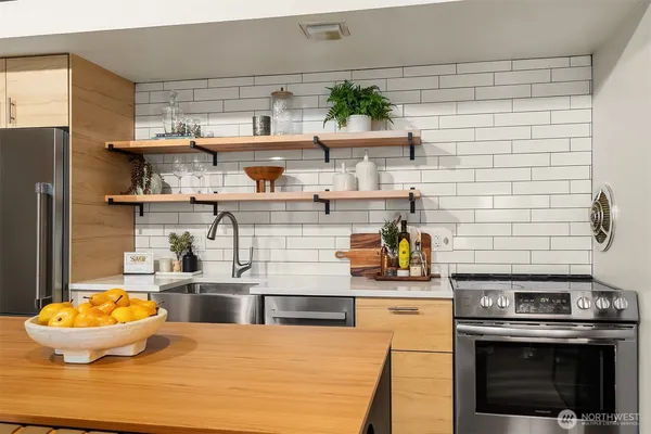 a kitchen with stainless steel appliances a stove and a wooden floor