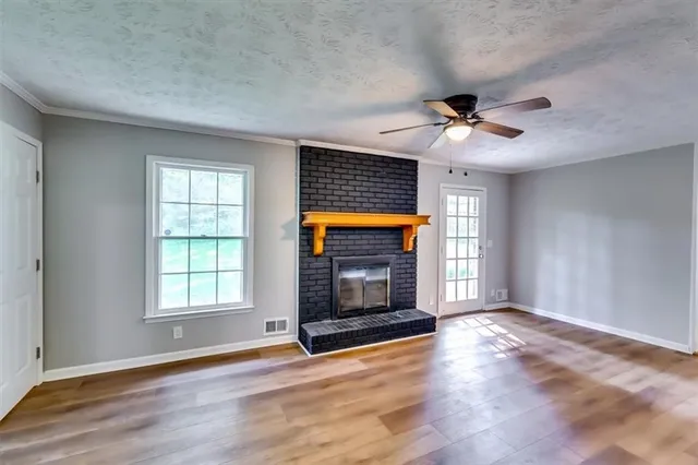an empty room with wooden floor fireplace and windows