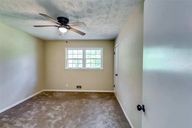an empty room with a window and a fan