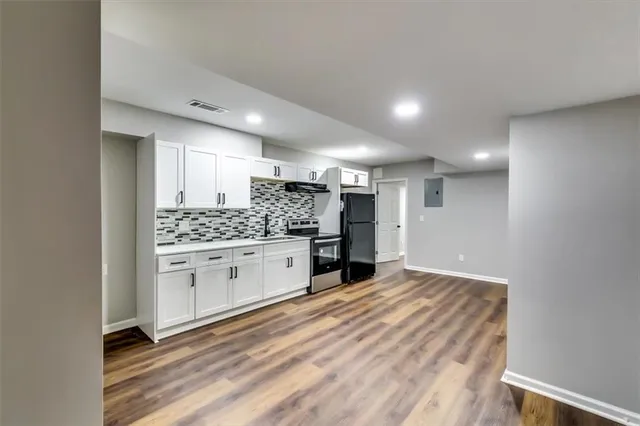 a large white kitchen with a sink and dishwasher a stove top oven with wooden floor