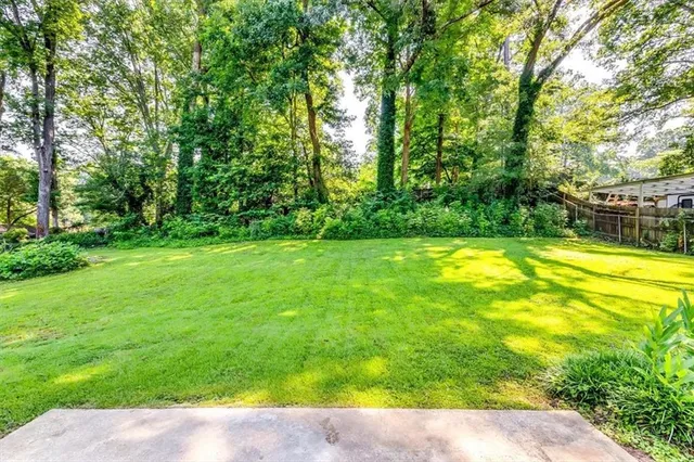 a view of house with a big yard and large trees