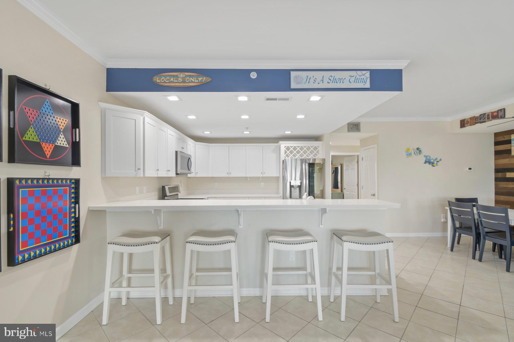 310 2nd Street, Unit 101 Ocean City, MD 21842 - Photo 8 of 37 a kitchen with stainless steel appliances kitchen island granite countertop a dining table chairs sink and cabinets
