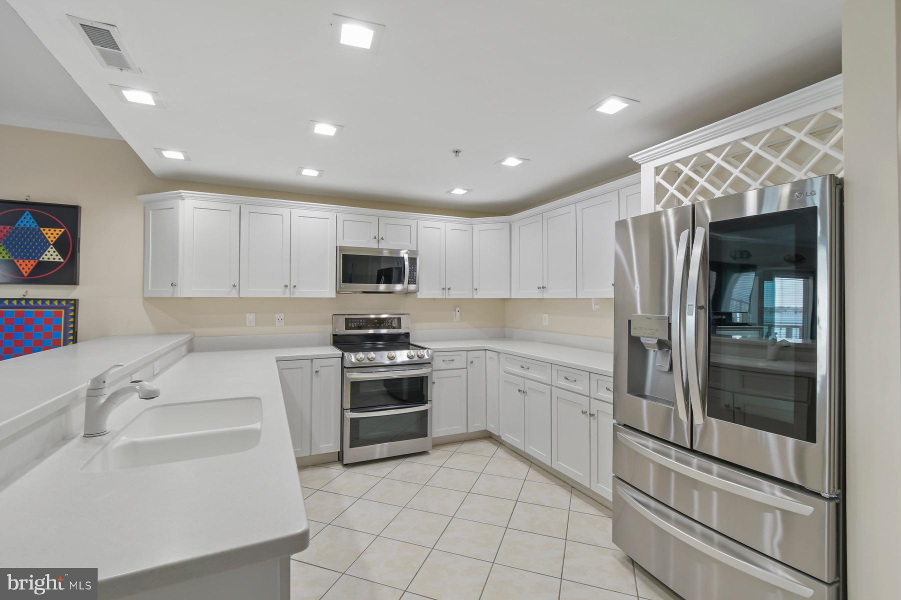 310 2nd Street, Unit 101 Ocean City, MD 21842 - Photo 10 of 37 a kitchen with white cabinets and stainless steel appliances