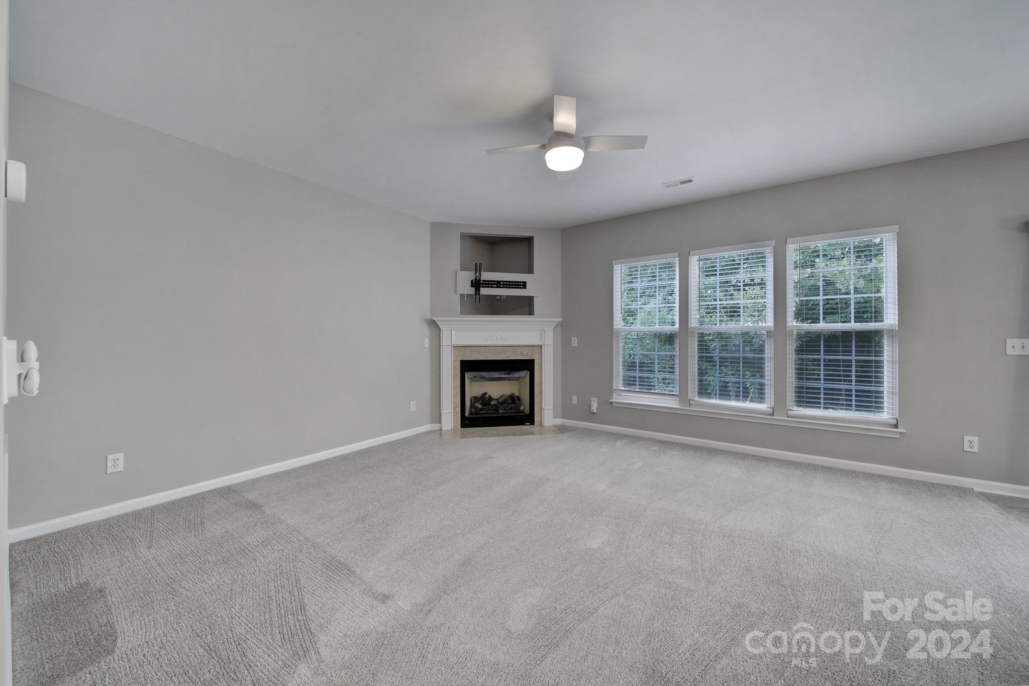 3305 Adair Marble Street Fort Mill, SC 29708 - Photo 12 of 38 an empty room with a fireplace and windows