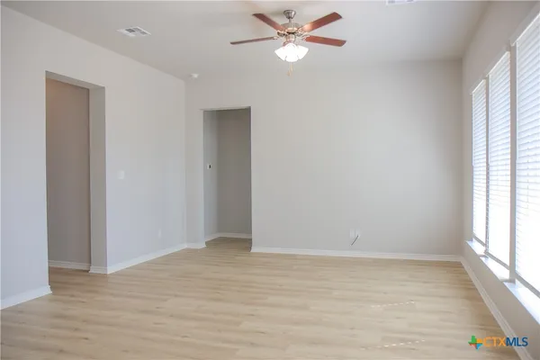 a view of empty room with wooden floor and fan