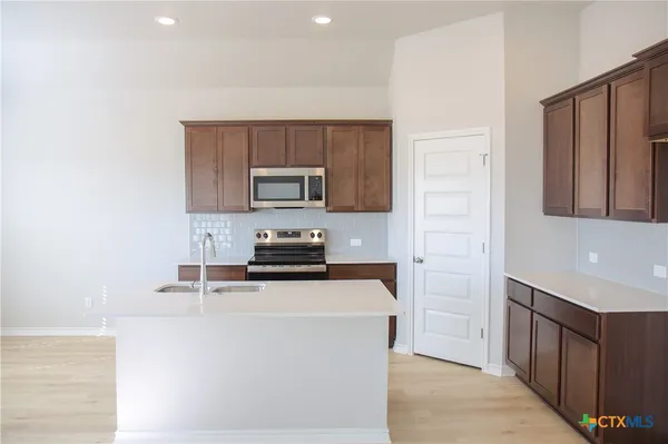 a kitchen with a refrigerator a stove top oven a sink and cabinets