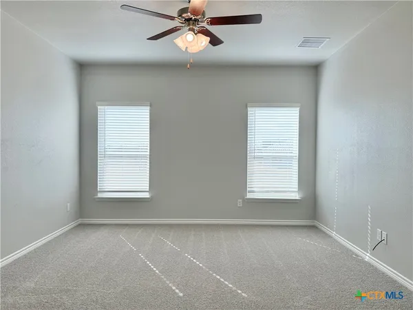 an empty room with windows and fan
