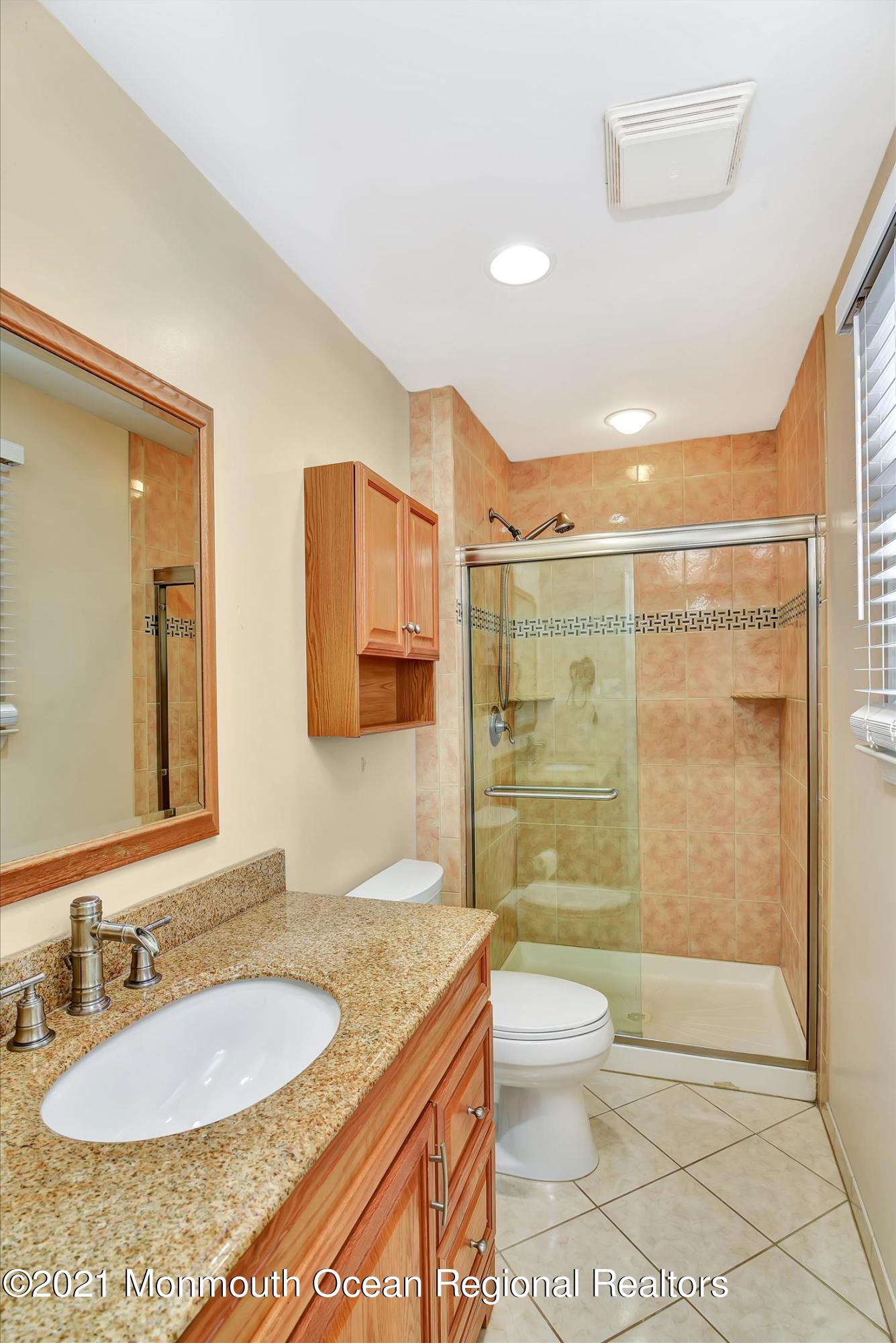 63 Hedgewood Road Howell, NJ 07731 - Photo 20 of 25 a bathroom with a granite countertop sink a toilet a mirror and shower