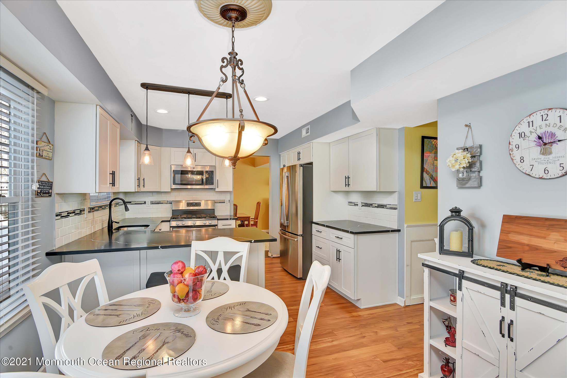 63 Hedgewood Road Howell, NJ 07731 - Photo 8 of 25 a kitchen with stainless steel appliances granite countertop a sink a stove a dining table and chairs with wooden floor
