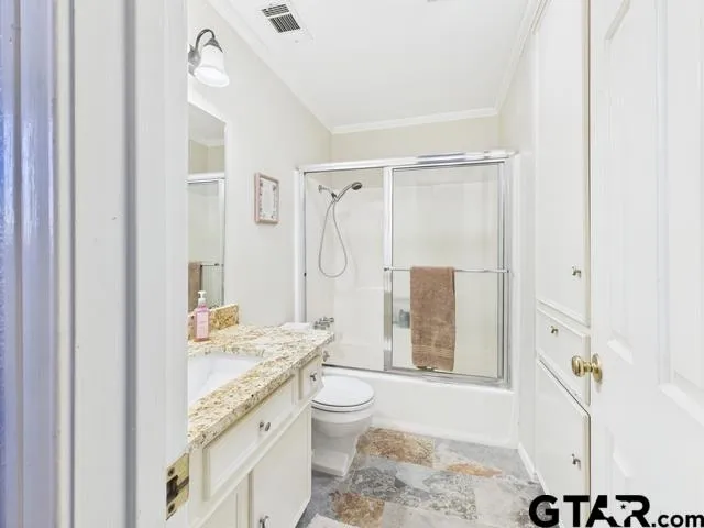 a bathroom with a granite countertop sink a toilet and shower