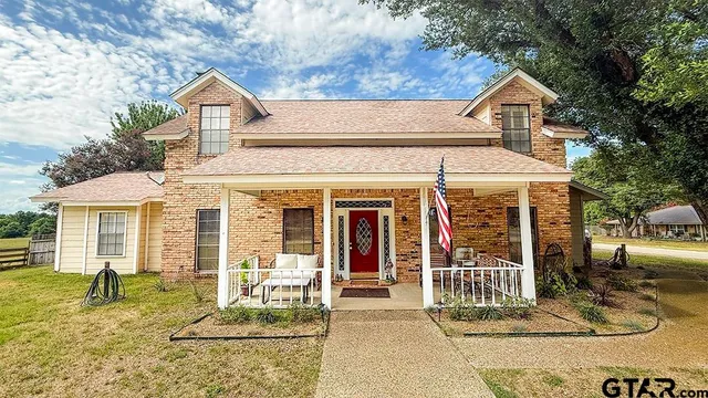 a view of a white house with large windows and a large tree