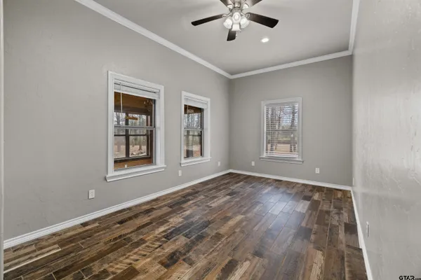an empty room with wooden floor chandelier fan and windows