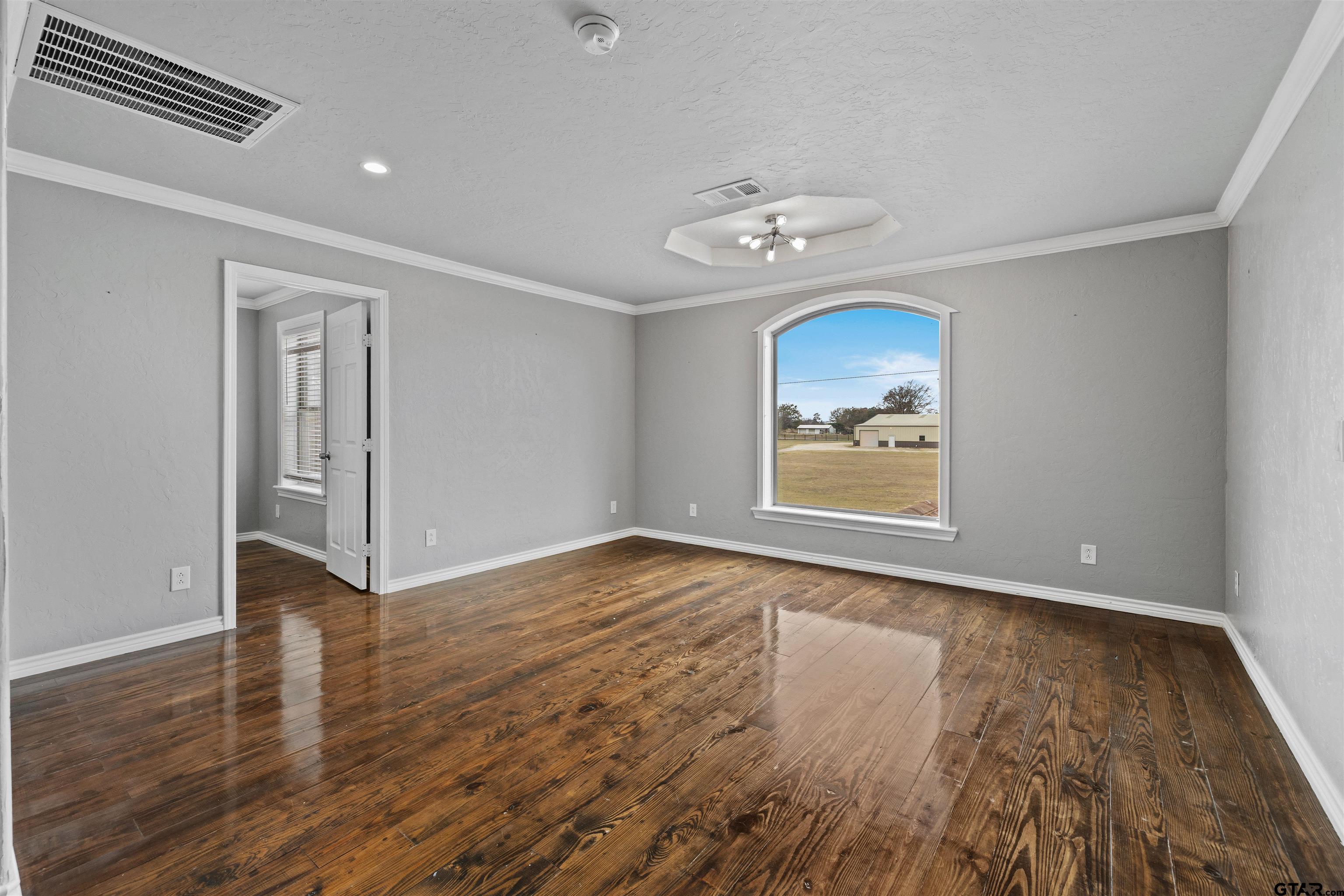5796 Highway 271 Pittsburg, TX 75686 - Photo 18 of 43 an empty room with wooden floor chandelier fan and windows