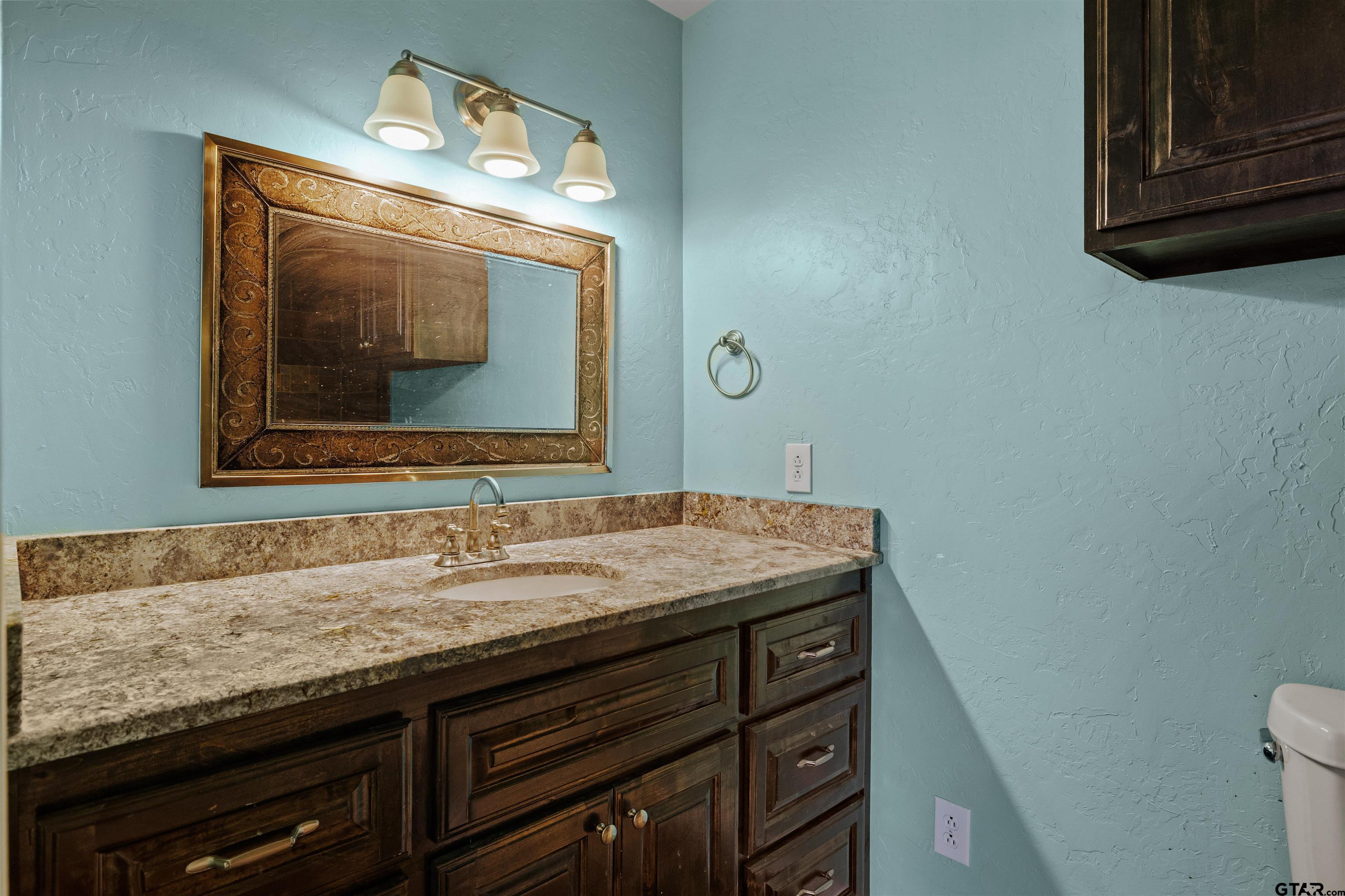 5796 Highway 271 Pittsburg, TX 75686 - Photo 27 of 43 a bathroom with a granite countertop sink a mirror and vanity