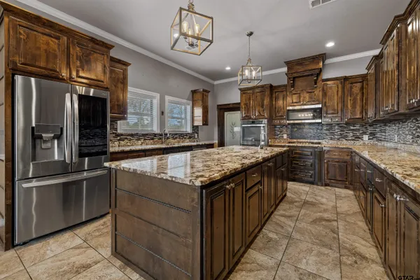 a kitchen with kitchen island granite countertop wooden cabinets and a stove top oven