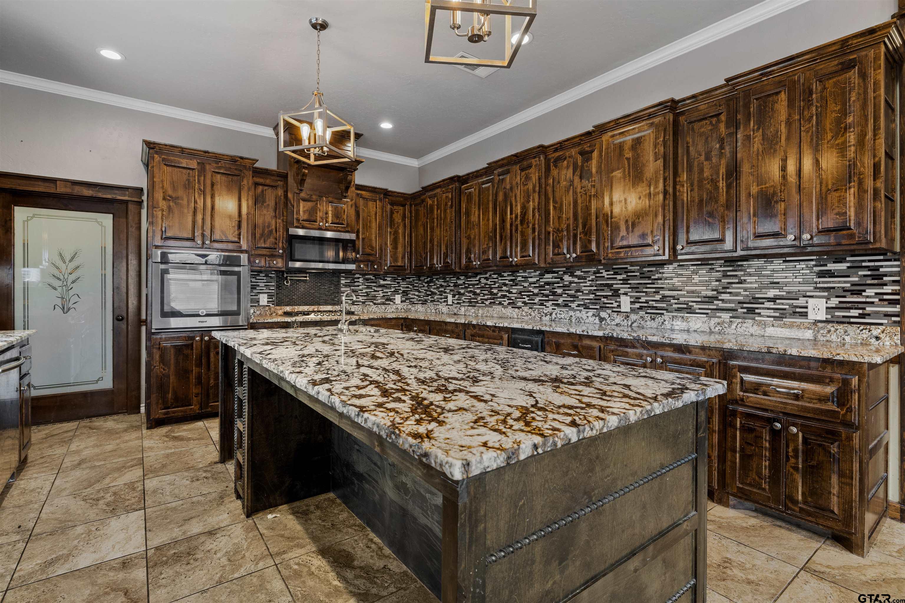 5796 Highway 271 Pittsburg, TX 75686 - Photo 7 of 43 a kitchen with kitchen island granite countertop wooden cabinets and a stove top oven