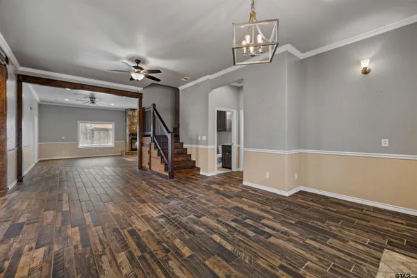an empty room with wooden floor a ceiling fan and windows