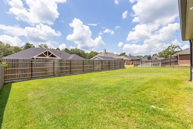 a view of a large ground with swimming pool and brick wall