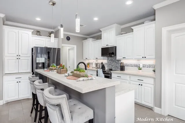a kitchen with a sink a stove a refrigerator and white cabinets with wooden floor