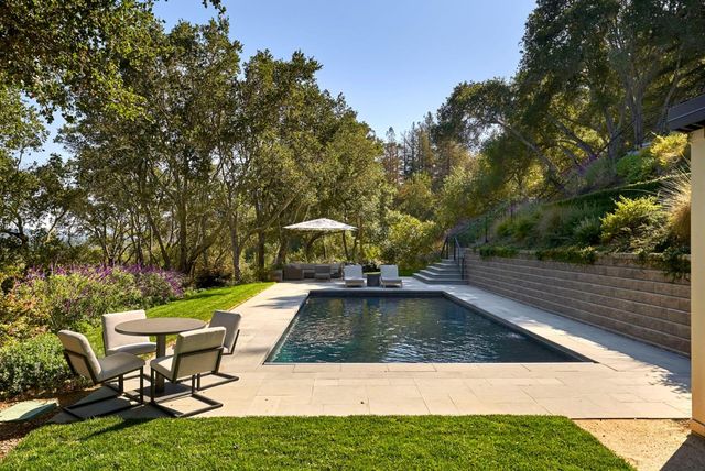 a view of a swimming pool with lawn chairs under an umbrella