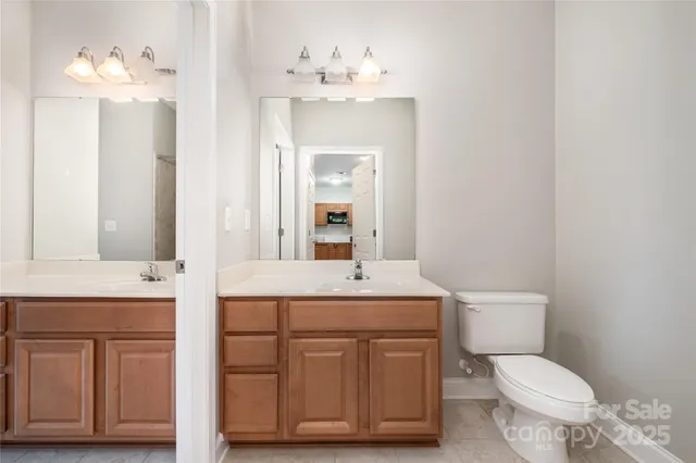 a bathroom with a sink vanity granite toilet and a mirror