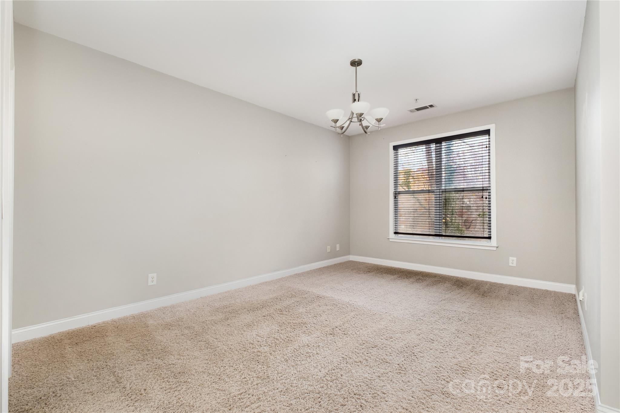 1000 East Woodlawn Road, Unit 217 Charlotte, NC 28209 - Photo 8 of 19 an empty room with a chandelier fan and windows