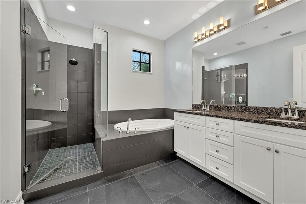 9154 Chula Vista Street, Unit 1331 Naples, FL 34113 - Photo 11 of 25 a spacious bathroom with a double vanity sink a mirror and a bathtub