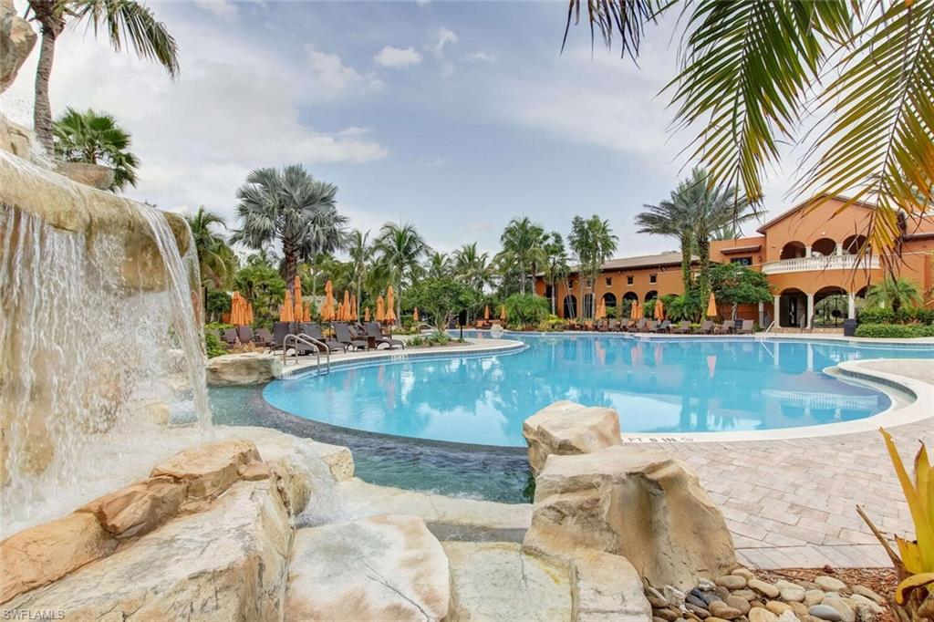 9154 Chula Vista Street, Unit 1331 Naples, FL 34113 - Photo 17 of 25 a view of a swimming pool with a lawn chairs under palm trees