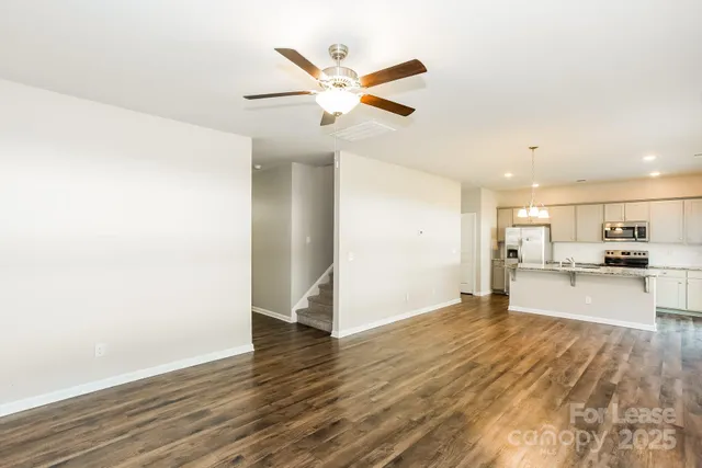 a view of a livingroom with a kitchen island wooden floor and a ceiling fan