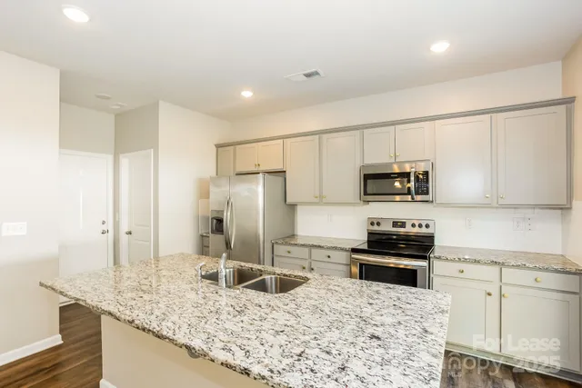 a kitchen with stainless steel appliances granite countertop a sink stove and refrigerator