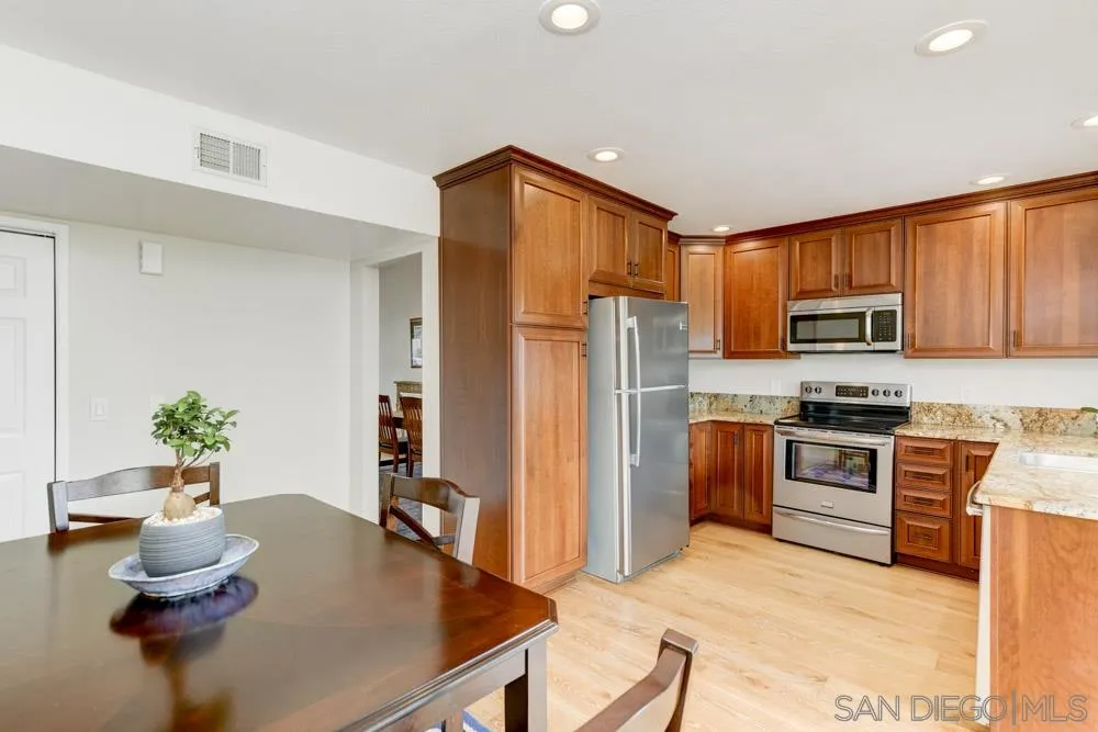 433 Village Run East Encinitas, CA 92024 - Photo 8 of 25 a kitchen with stainless steel appliances granite countertop a refrigerator a stove top oven a sink dining table and chairs