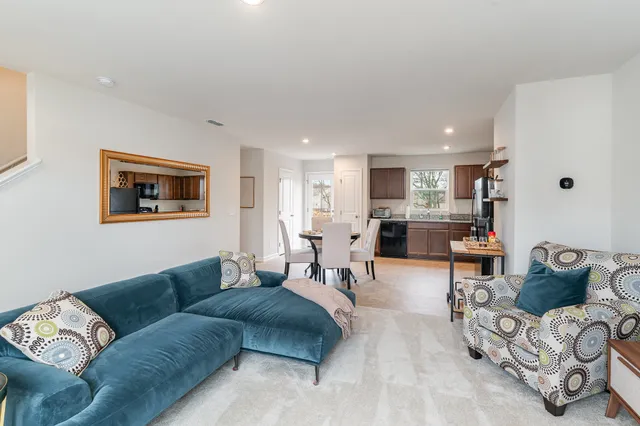 a living room with furniture kitchen view and a window