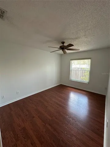 an empty room with wooden floor fan and windows