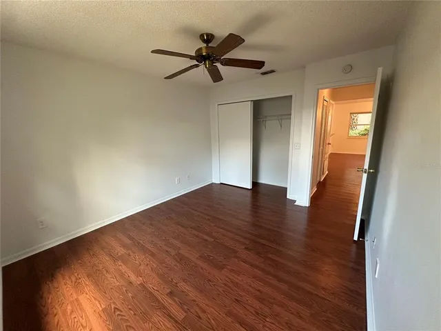 a view of empty room with wooden floor and ceiling fan